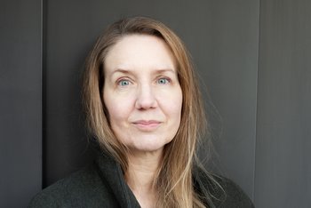 Gesicht der Autorin frontal, hellblaue Augen, lange blonde Haare, schwarzes Hemd