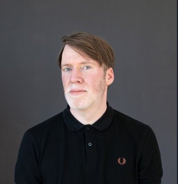 Autor im Halbprofil, schwarzer Rollkragenpullover, braunes Haar im Seitenscheitel, weißer Bart